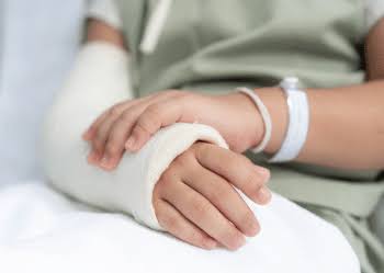 A patient with a bandaged hand and wrist receiving fracture care in hospital